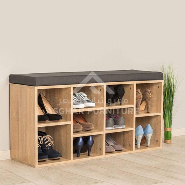 A functional wooden shoe cabinet with multiple cubbies filled with various shoes, topped with a dark grey padded bench.