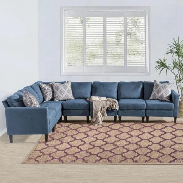 A large modular sectional sofa in medium blue fabric sits on a tan and purple geometric rug.