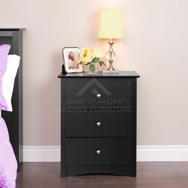 A classic black nightstand with two drawers and silver knobs, topped with a lamp and framed picture.