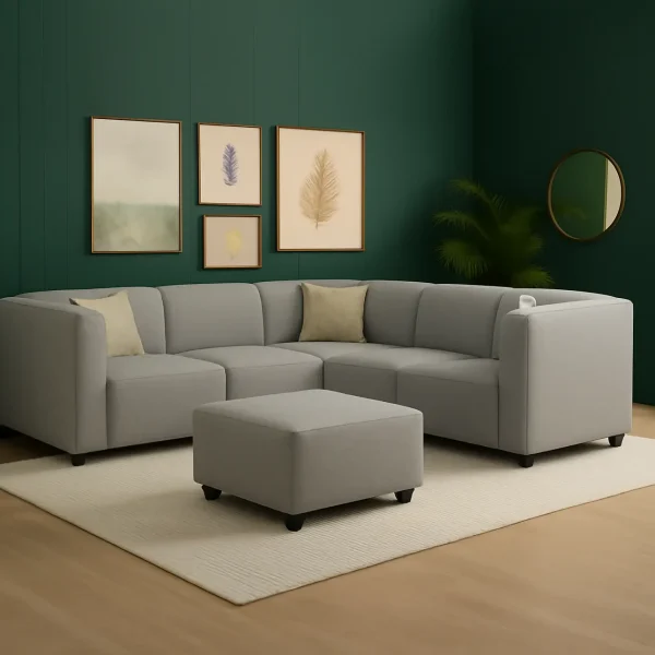A modern light gray modular corner sectional sofa with a matching ottoman, against a dark green accent wall.