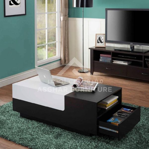 A black and white rectangular coffee table with a white cushion and a large pull-out drawer.