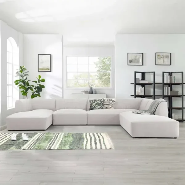 A large U-shaped modular sectional sofa in light beige/off-white fabric, placed on a green and white abstract rug.