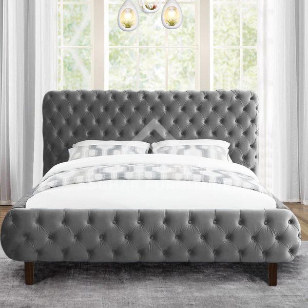 A sophisticated grey velvet tufted bed with a high headboard and footboard, positioned by a window.