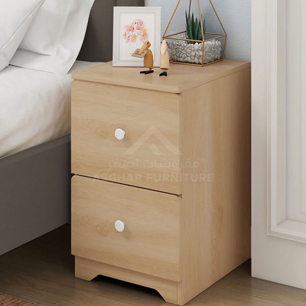 A light wood nightstand with two drawers and white knobs, topped with a picture frame and a geometric plant holder.