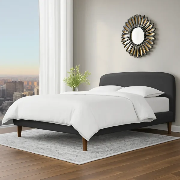A contemporary dark gray upholstered bed with a rounded headboard, and a flower-shaped mirror on the wall.