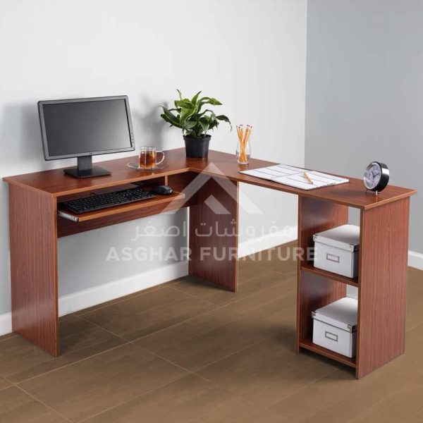 A wooden L-shaped computer desk with a monitor, keyboard tray, and open shelving on one side.