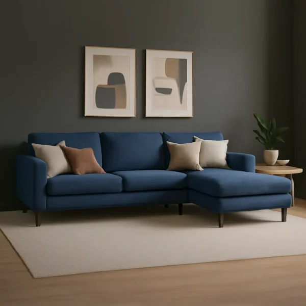 A blue L-shaped sectional sofa with a right-hand chaise lounge, accented with pillows, in front of a dark gray wall.