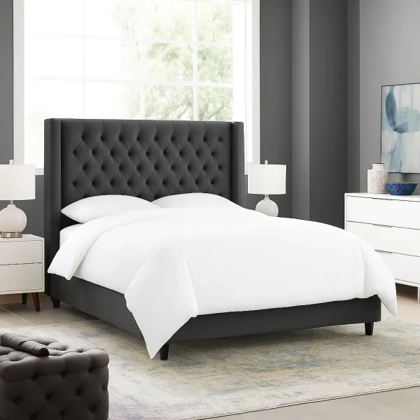A modern dark gray tufted upholstered bed with a high wingback headboard.