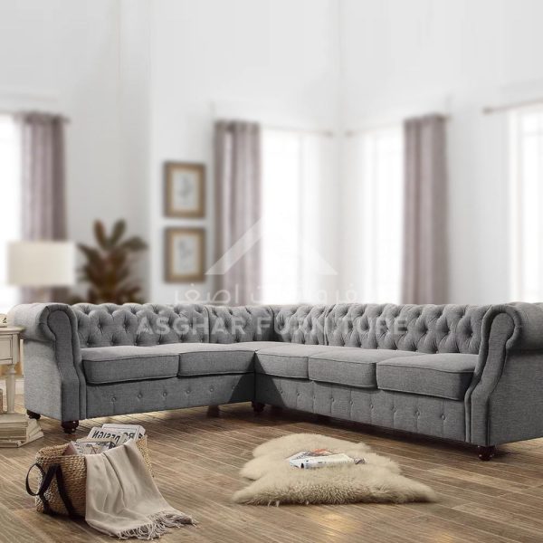 A traditional gray L-shaped sectional sofa with deep button tufting and rolled arms, sitting on a wooden floor.