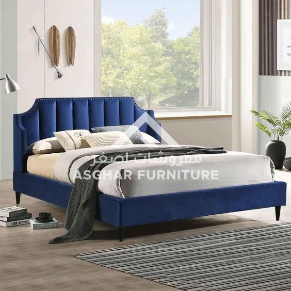 A royal blue velvet upholstered bed with a channel-tufted headboard and nailhead trim.