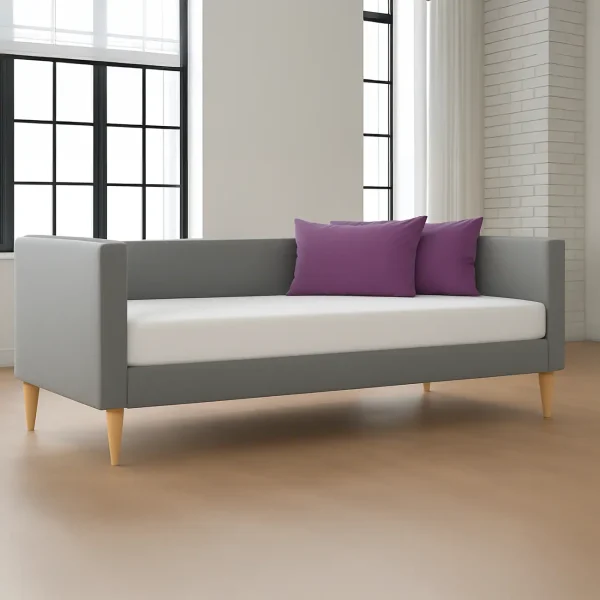 An grey daybed with a clean white mattress, two vibrant purple pillows, and light wooden tapered legs.