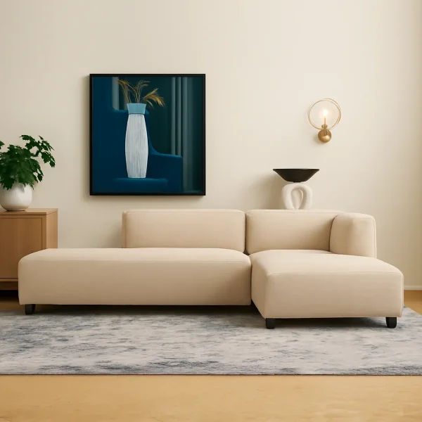 A modern, L-shaped cream sofa with a left-hand chaise lounge, a large abstract painting on the wall, and a gold wall sconce.