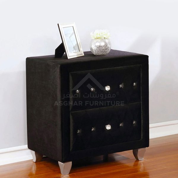 A contemporary black velvet tufted nightstand with two drawers and crystal knobs.