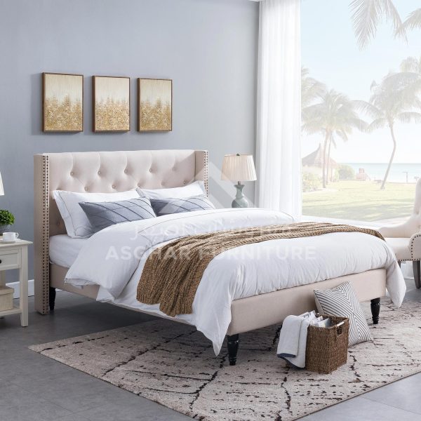 A beige tufted wingback bed with nailhead trim, white bedding, and a cozy brown knit throw.