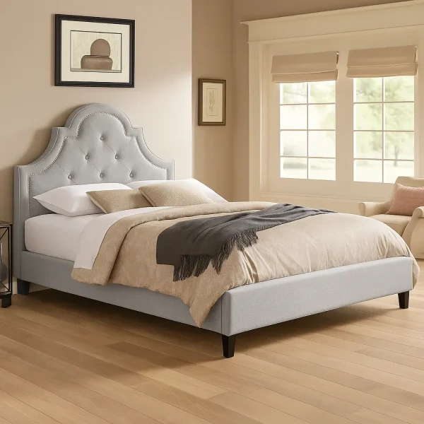 A graceful light grey upholstered bed with a curved, tufted headboard and natural wood flooring.