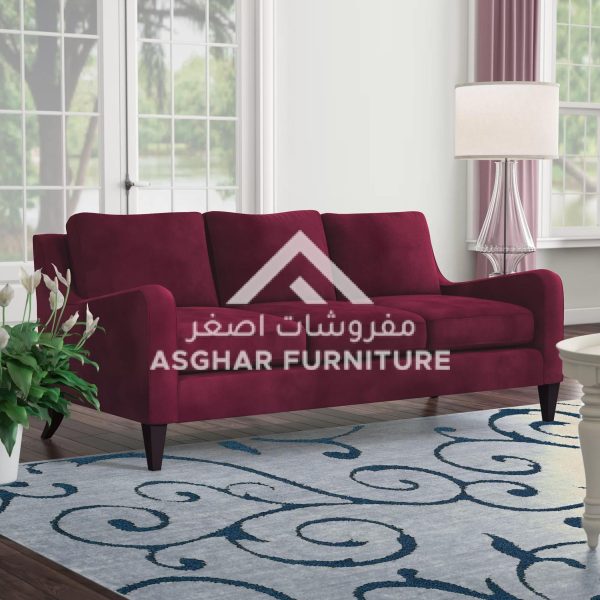 A dark red, three-seater sofa with decorative pillows and a vintage-style rug in a modern living room.