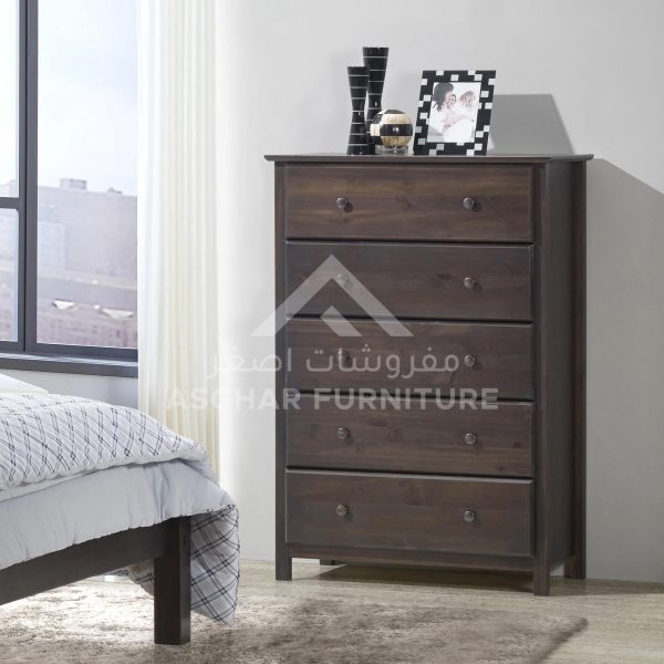 A classic dark wood five-drawer dresser with round knobs, adorned with a framed photo and decor.