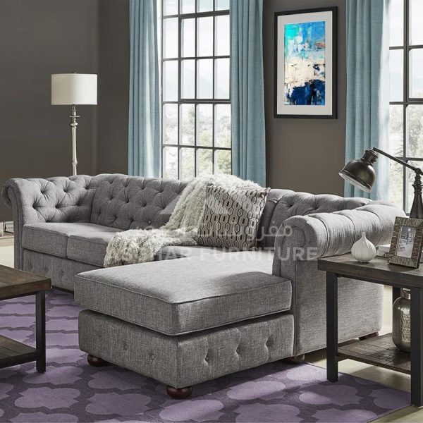 A light gray tufted chesterfield sofa with a chaise lounge, a throw blanket, and a purple geometric rug.