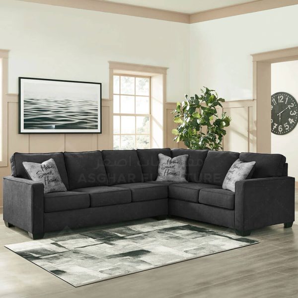 A black fabric sectional sofa with pillows, and a black and white patterned rug.
