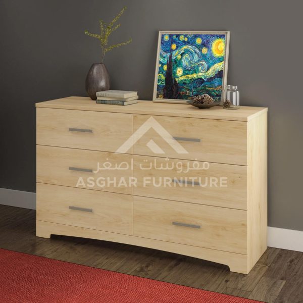 A six-drawer light wood dresser with silver handles, topped with a vase, books, and a starry night painting.
