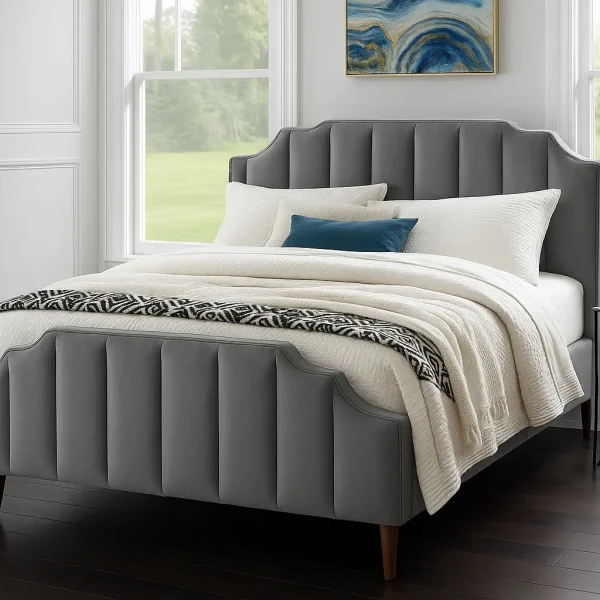 A plush gray scalloped bed with white and patterned bedding, under a blue abstract artwork.