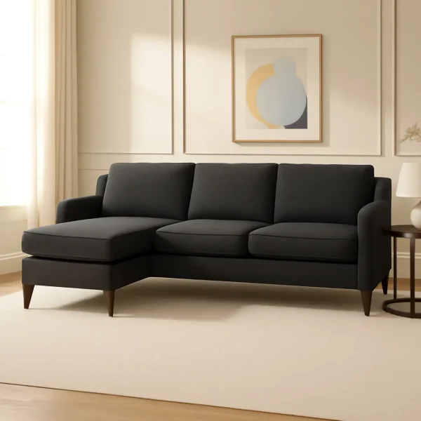 A dark gray L-shaped sectional sofa with a chaise lounge. The sofa has a simple, modern design with cushioned backrests and straight, tapered wooden legs.