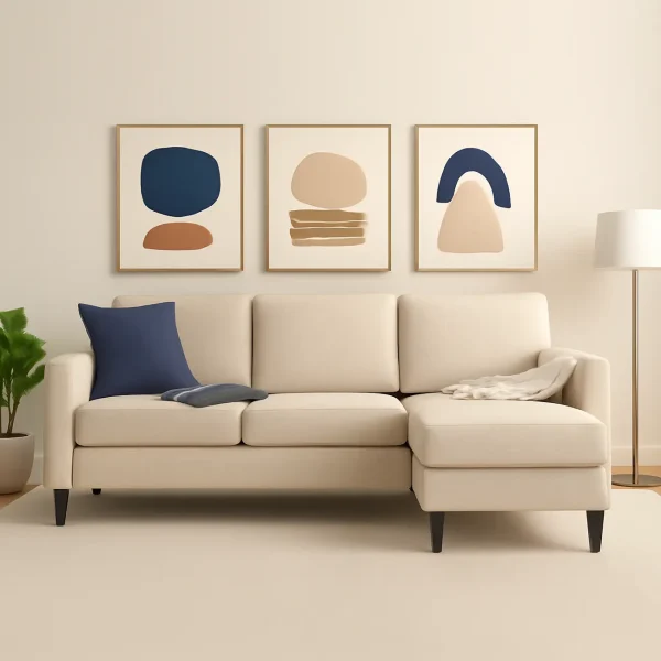 A beige L-shaped sectional sofa with a chaise lounge and dark wooden legs. The sofa is decorated with a navy throw pillow and a cream-colored blanket.