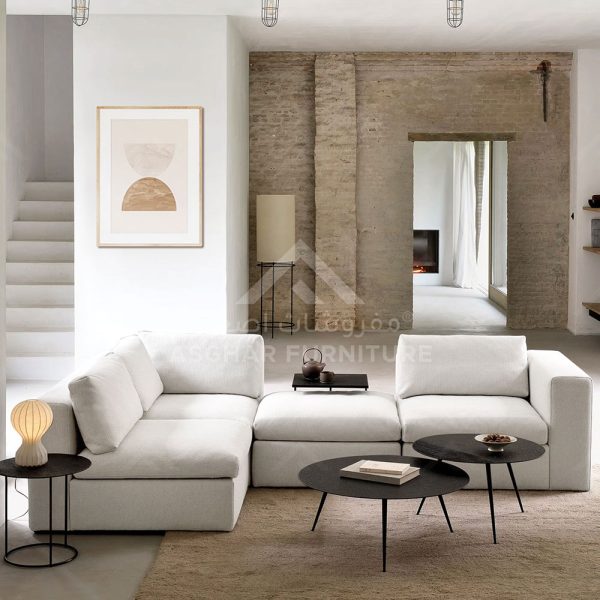 A white modular sectional sofa with two round black coffee tables, and a large abstract art print on the wall.