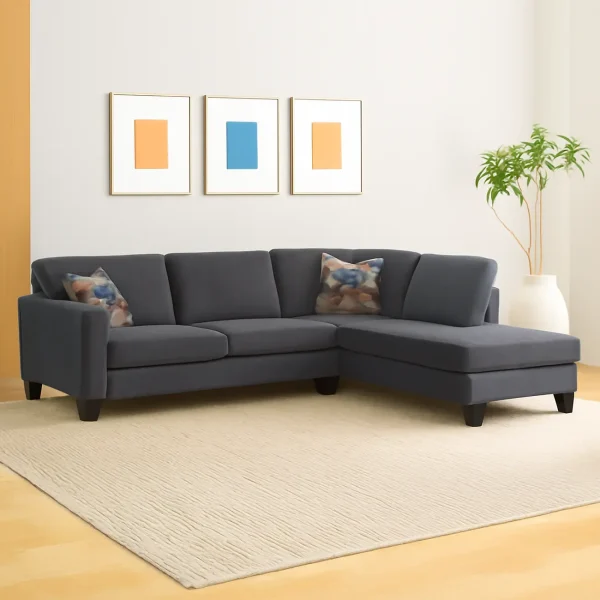 A dark gray L-shaped sectional sofa with a right-hand chaise lounge, a white rug, and three framed art prints.