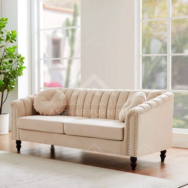 A modern beige sofa with a tufted back and sides, decorative studs, and two round pillows.