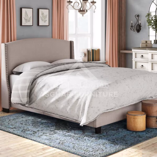 A sophisticated beige upholstered bed with a studded headboard, white bedding, and a blue patterned rug.
