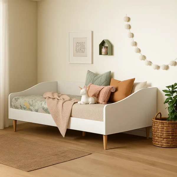 A cute white daybed with a patterned mattress, styled with pillows, a throw, and a unicorn toy.