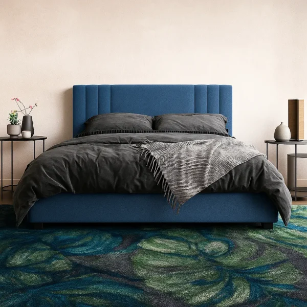 A modern blue channel-tufted bed with dark gray bedding and a vibrant green and blue floral rug.