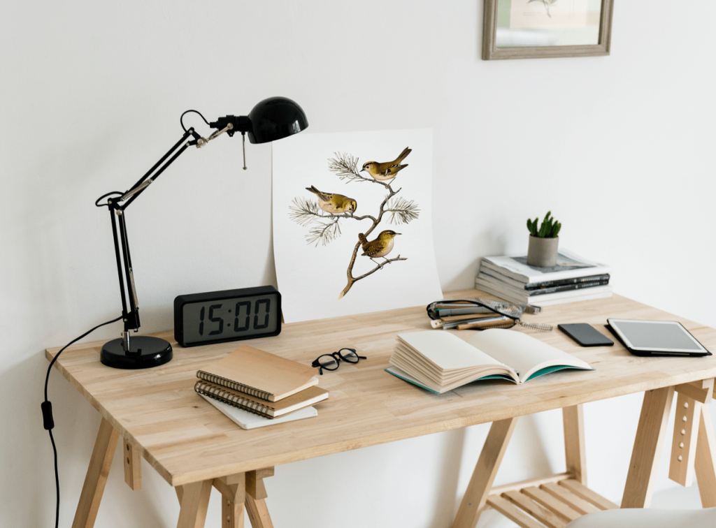 A neatly arranged desk featuring a lamp, several books, and a clock, creating a cozy study environment.