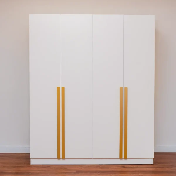 A minimalist four-door white wardrobe with tall, vertical gold handle pulls.
