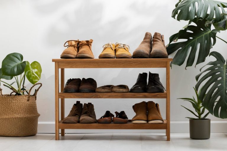 A wooden shoe rack displaying various shoes alongside potted plants for a stylish and organized entryway.