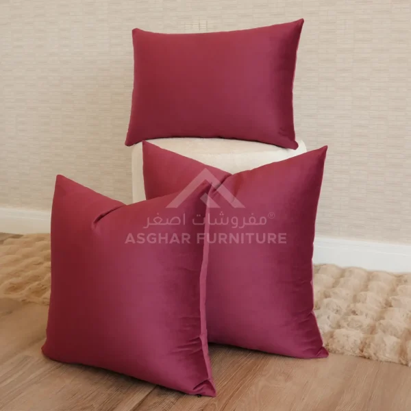 A stack of three deep red satin-like cushions, with one rectangular and two square.