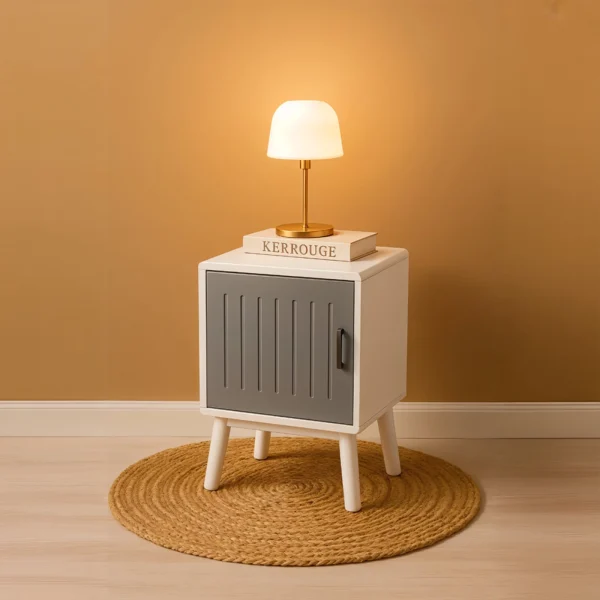 A white and grey cabinet on white legs, topped with a lamp and a book, on a round jute rug.