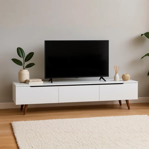 A sleek white TV stand with three drawers and wooden legs, displaying a large TV and decor.