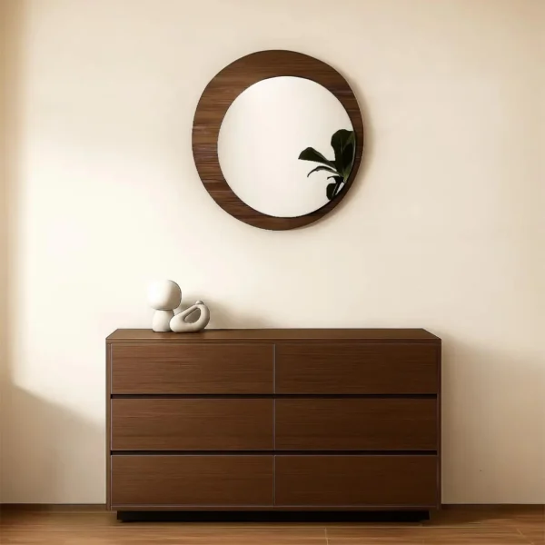 Modern dark wood six-drawer dresser with a round wall mirror in a home.
