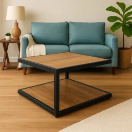 A blue sofa and a plant sit in the background behind a square, modern coffee table with wood accents.
