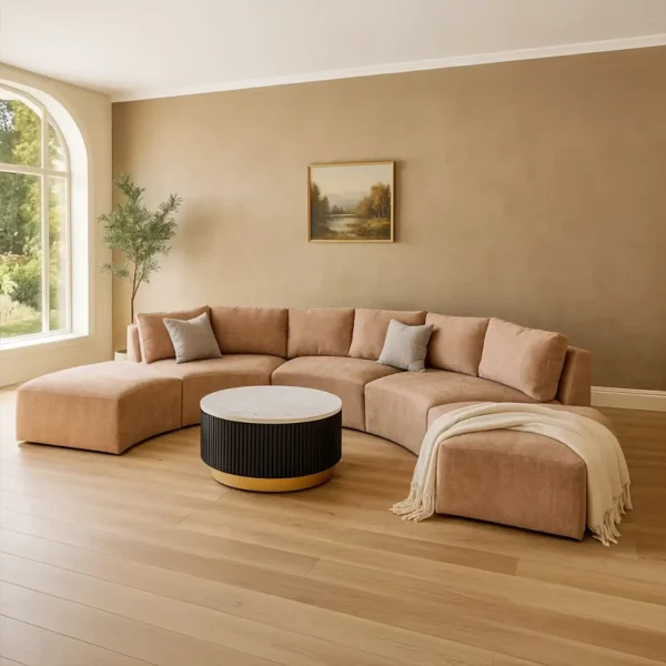A contemporary beige sofa and ottoman with a round coffee table with a white marble top.