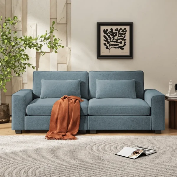 A two-seat, light blue sofa with an orange throw blanket and pillows in a modern living room.