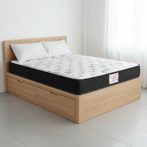A mattress with a black quilted side and white top rests on a light wood platform bed with two storage drawers.