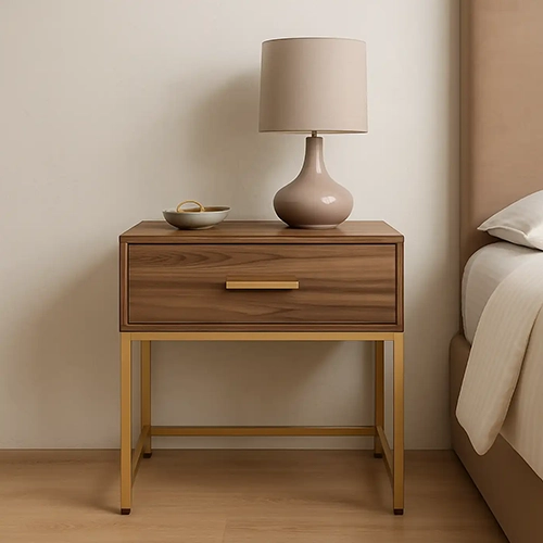 A wooden nightstand with a single drawer and a gold metal frame, topped with a lamp.