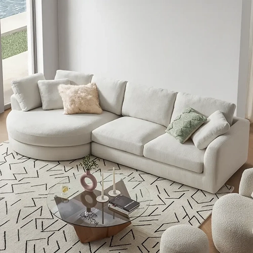 A light, off-white L-shaped sectional sofa with a round chaise lounge is in a modern living room.