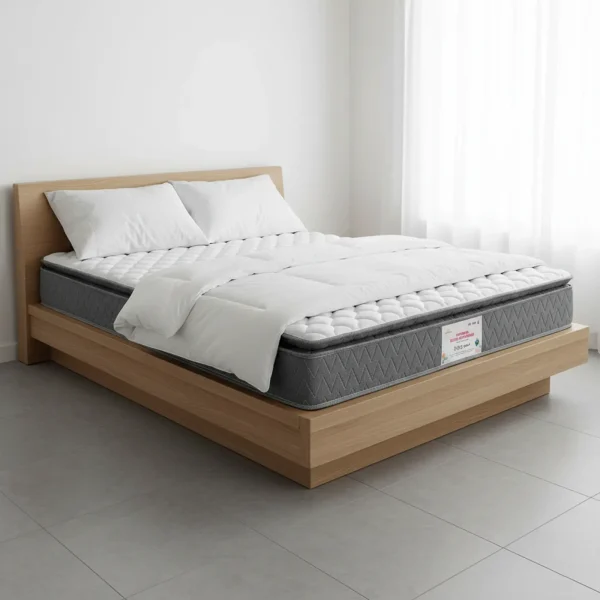 A thick gray mattress with a quilted pillow top rests on a simple light wood platform bed.
