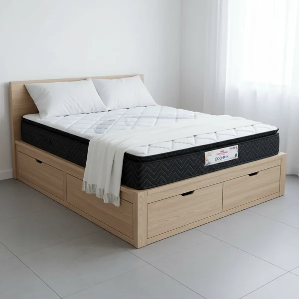 A thick pillow-top mattress with a black quilted border on a light wood storage bed.