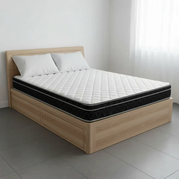 A white quilted mattress with a black and white patterned side on a light wood storage bed.