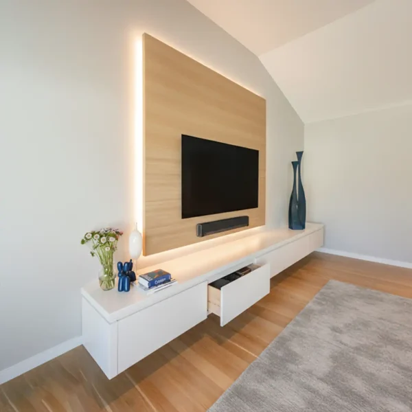 A floating white media console with a long drawer beneath a light wood wall panel with vertical LED lighting.